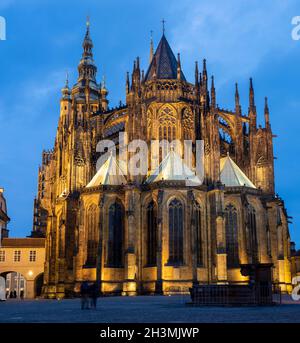 Facciata posteriore (est) della Cattedrale di San Vito illuminata di notte: L'esterno gotico dettagliato della parte posteriore della cattedrale è evidenziato dai fari di luce come la notte cade. Un certo numero di toursts passa vicino. Foto Stock