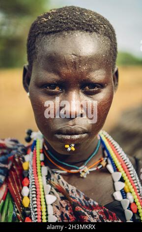 Tribù TOPOSA, SUDAN DEL SUD - 12 MARZO 2020: Donna di Toposa Tribe che indossa perline colorate tradizionali e piercing e guardare Foto Stock