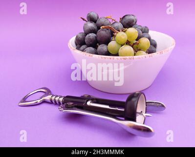 vino rosso e uve bianche e tappi su sfondo viola, foto Foto Stock