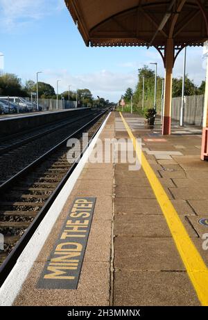 Ottobre 2021 - attenzione al passo di avvertimento sul bordo della piattaforma presso la stazione ferroviaria di Yatton in Rural Somerset, Inghilterra, Regno Unito. Foto Stock