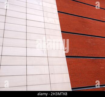 Un muro di mattoni rossi con linee nere diviso a metà da grandi piastrelle bianche moderne in pietra Foto Stock