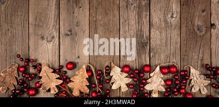 Banner di Natale con decorazioni in legno e baubles rossi. Vista dall'alto su sfondo di legno invecchiato. Foto Stock