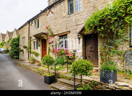 Porta d'ingresso e rose rosa in un cottage a Castle Combe, un pittoresco villaggio nella Cotswolds Area di bellezza naturale nel Wiltshire, Inghilterra sud-occidentale Foto Stock