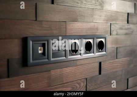 Interruttori e prese elettriche per uso domestico in primo piano. Interni dal design minimalista. Elegante camera da letto e soggiorno. Muro di mattoni in legno in un designer Foto Stock