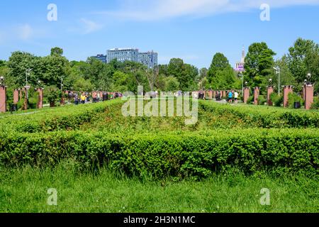 Bucarest, Romania - 15 Aprile 2021: Paesaggio con erba, rose e grandi alberi verdi verso il cielo azzurro nel Parco Re Michele i (Herastrau), i Foto Stock