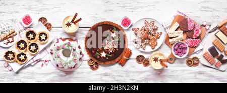 Vari dolci e dolci natalizi. Vista dall'alto della scena del tavolo su uno sfondo di legno bianco. Torta Bundt, torta al cioccolato, crostate di carne macina Foto Stock