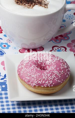 Ciambella rosa e una tazza di cappuccino Foto Stock