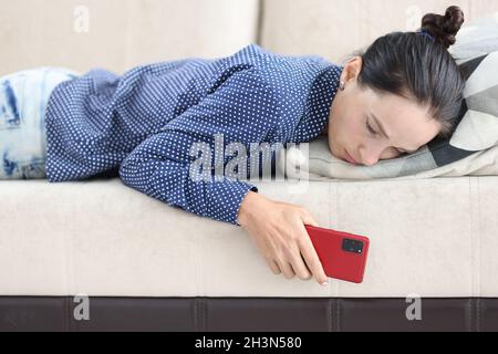 Donna triste si trova sul divano con smartphone primo piano Foto Stock