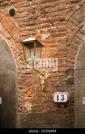 Casa numero 13 su mattoni vecchia parete e moderna lampadina a risparmio energetico in antica lampada da strada Foto Stock