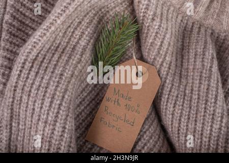 Etichetta realizzata con tessuto riciclato e decorata con un ramo di albero di Natale. Moda ecologica e sostenibile. Foto Stock