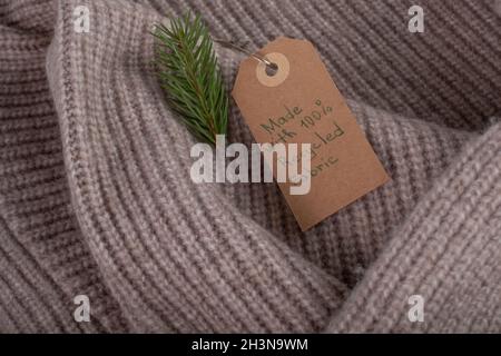 Etichetta realizzata con tessuto riciclato e decorata con un ramo di albero di Natale. Moda ecologica e sostenibile. Foto Stock