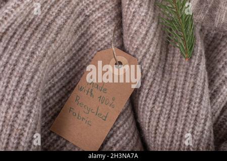 Etichetta realizzata con tessuto riciclato e decorata con un ramo di albero di Natale. Moda ecologica e sostenibile. Foto Stock