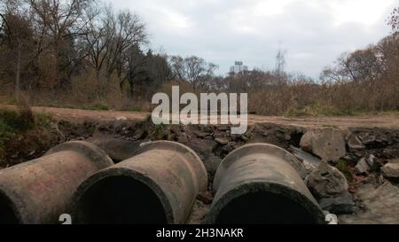 Tubi per rifiuti in calcestruzzo. Flussi di acqua fluiscono attraverso tubi di calcestruzzo. Corpo inquinato di acqua nel parco. Tiro dal drone. Fotografia aerea. Foto Stock