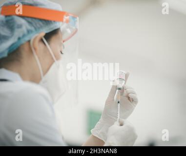 Infermiera con una divisa medica preparandosi per un'iniezione di vaccinazione Foto Stock