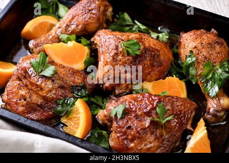 Appetitose fette di pollo al forno con crosta fritta croccante e arance in una teglia da forno Foto Stock