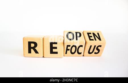 Rifocalizzazione e riapertura del simbolo. L'uomo d'affari girò i cubi e cambiò la parola 'focus' in 'reopen'. Bella tavola bianca, sfondo bianco. Business refo Foto Stock