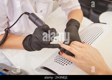 Manicurista rimozione cuticola su mano donna con chiodo trapano elettrico Foto Stock