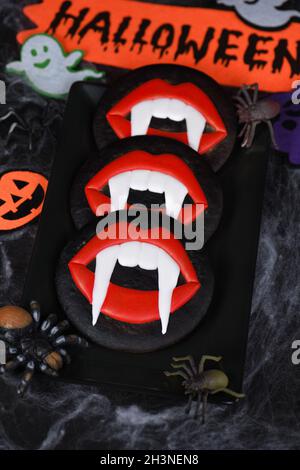 I pani di vampiro che sporgono dalle labbra scarlatto, biscotti di pan di zenzero di miele smaltati. Idea alimentare di Halloween Foto Stock