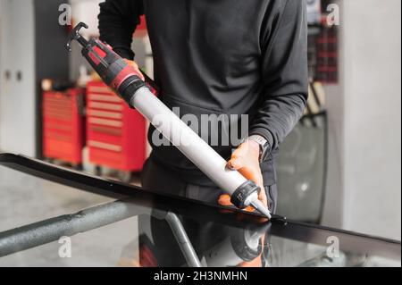 Glazier applicare la guarnizione di gomma al parabrezza in garage, primo piano. Foto Stock