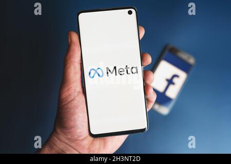 META logo sullo smartphone tenuto in mano davanti al telefono con l'icona Facebook. Facebook cambia il nome della società in Meta e si concentra sulla metaversa nel suo rebrand. Swansea, Regno Unito - 30 ottobre 2021. Foto Stock