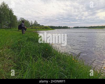 Un uomo che cattura il pesce di fronte ad un fiume in Finlandia. Foto Stock