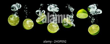 Mazzetto di frutti di lime metà affondando con bolle in acqua isolato su sfondo nero Foto Stock