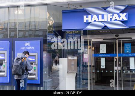 Un cliente visita la filiale di Halifax con Cash Machine sulla parete frontale accanto all'ingresso principale della banca di vendita al dettaglio London England UK Foto Stock