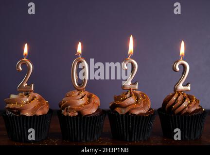 Buon Capodanno 2022 cupcake al cioccolato decorate con candele dorate Foto Stock