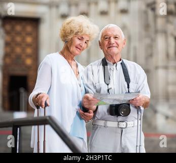 Donna anziana e uomo che viaggiano insieme alla ricerca di una destinazione con la mappa della città Foto Stock