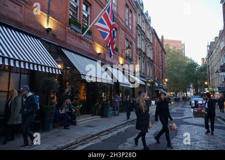 Londra, UK, 29 ottobre 2021: Mentre il crepuscolo cade a Covent Garden e nelle strade acciottolate circostanti, i turisti e gli amanti dello shopping godono di un incantesimo secco tra le docce a pioggia. I ristoranti e i ristoratori di bar, pub o ristoranti hanno spesso la scelta di sedersi all'interno o all'esterno. Le campagne pubblicitarie volte a incoraggiare le persone a visitare Londra sembrano aver attirato molte visite familiari a metà termine e Londra ha attualmente un tasso di infezioni da covid inferiore rispetto ad altre aree del paese. Le decorazioni natalizie sono già in alto nella zona centrale del mercato. Anna Watson/Alamy Live News Foto Stock