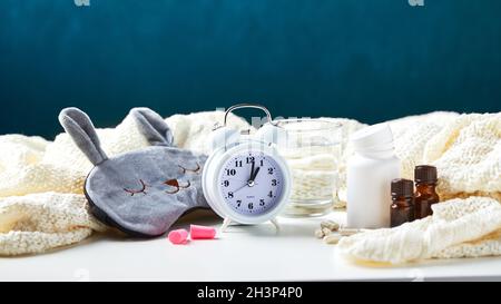 Maschera per dormire, sveglia, tappi per le orecchie e pillole. Concetto creativo di sonno notturno sano. Foto Stock