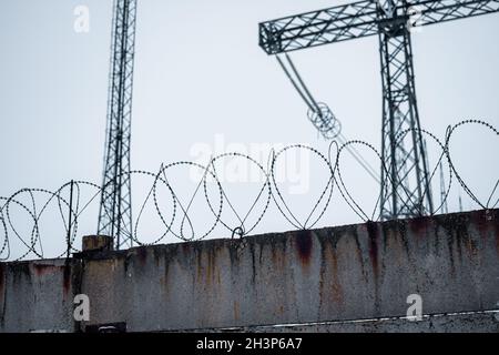 Recinzione con filo spinato. Linee di alimentazione ad alta tensione. Foto Stock