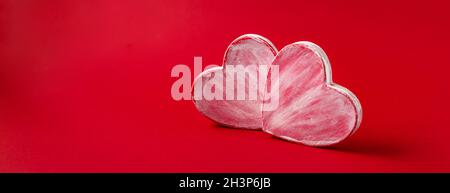 Due cuori valentini fatti di carta mache su sfondo rosso. Simbolo d'amore e di festa San Valentino. Foto Stock