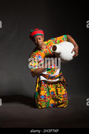 Uomo africano in abiti tradizionali sorriso toothy, su sfondo grigio Foto Stock