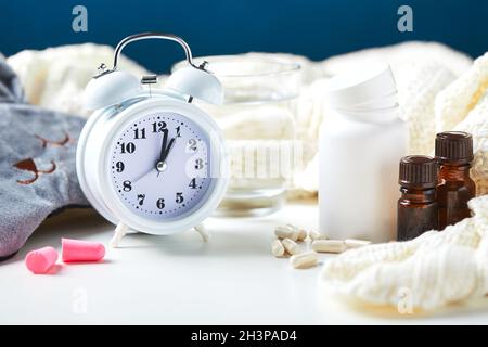 Maschera per dormire, sveglia, tappi per le orecchie e pillole. Concetto creativo di sonno notturno sano. Foto Stock