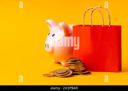 Concetto di shopping. Shopping bag con pila di monete Foto Stock