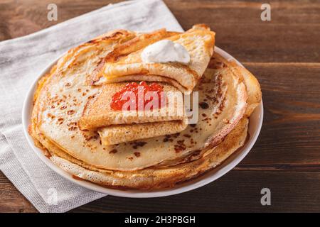 Pila di frittelle russe blini con caviale rosso, panna acida fresca Foto Stock