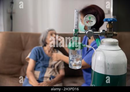 Donna anziana che indossa la canula nasale dell'ossigeno a casa. Foto Stock