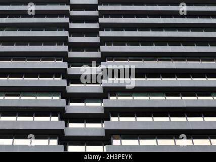 La facciata di un grande edificio urbano di uffici in cemento con file di finestre riflettenti Foto Stock