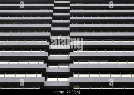 La facciata di un grande edificio urbano di uffici in cemento con file di finestre riflettenti Foto Stock