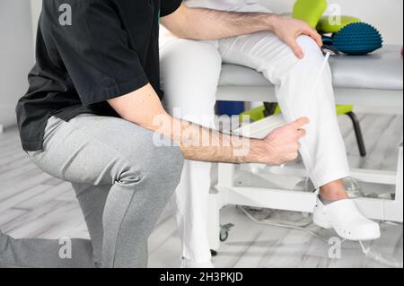 Esame neurologico. Il neurologo che esamina i riflessi su una paziente femminile utilizzando un martello. Foto Stock