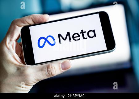 LOGO META Company visualizzato sullo smartphone con logo Facebook sullo schermo di sfondo. Nuovo logo aziendale Facebook per METAVERSE. Foto Stock