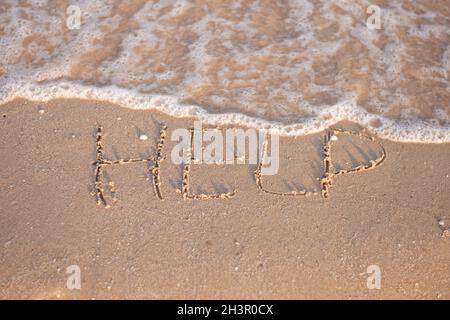 l'iscrizione aiuta sulla sabbia, sulla riva del mare Foto Stock