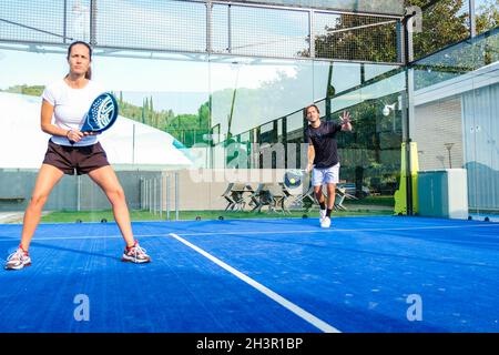 Misto padel match in una corte di erba blu padel - bella ragazza e bell'uomo giocare padel all'aperto Foto Stock