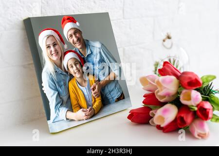 Foto stampata su tela, sfondo bianco. Felice giovane famiglia a Babbo Natale in casa Foto Stock