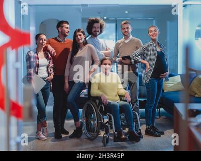 Donna d'affari disabile in sedia a rotelle in ufficio con colleghi team Foto Stock