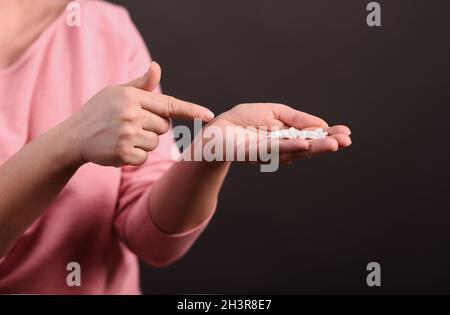 La donna punta alla manciata di pillole in mano. Foto Stock