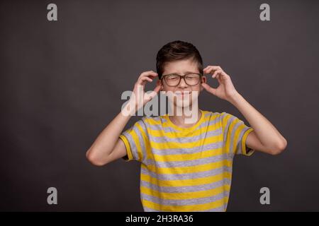 Un ragazzo adolescente con occhiali ha un mal di testa. Mock up Foto Stock