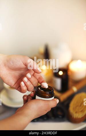 Cosmetologo femminile che applica crema facciale in salone Foto Stock