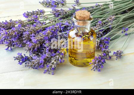 Olio essenziale di lavanda con fiori di lavanda su un rustico sfondo di legno con copyspace Foto Stock